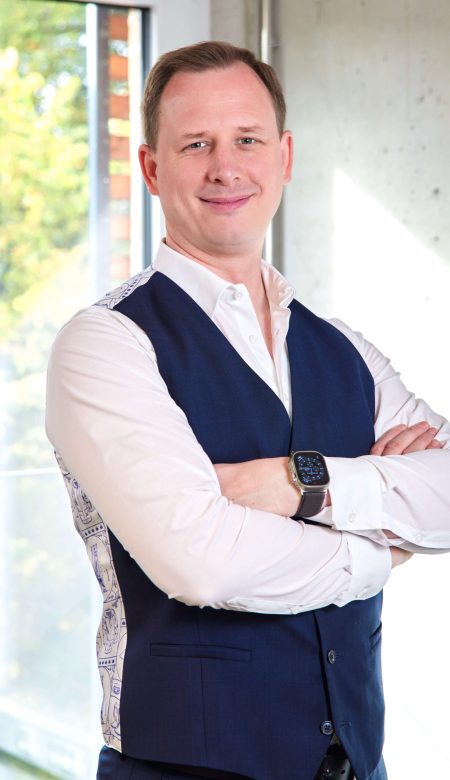 Steuerberater Tobias Hans Tobien steht mit verschränkten Armen vor einem hellen Hintergrund.